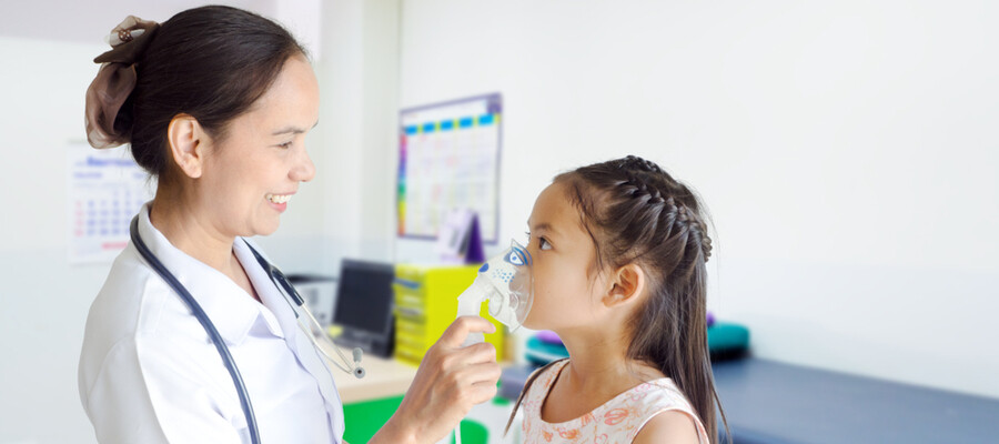 A respiratory therapist treats a young girl with asthma using a breathing mask to help her breathe.