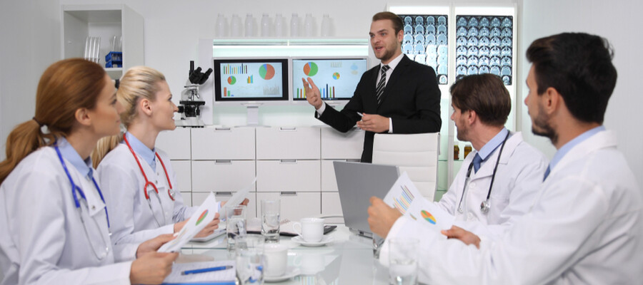 A healthcare administrator meets with a team of doctors in a hospital setting