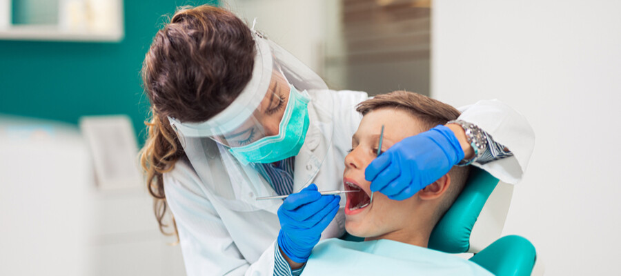 A dental hygienist works with a young patient