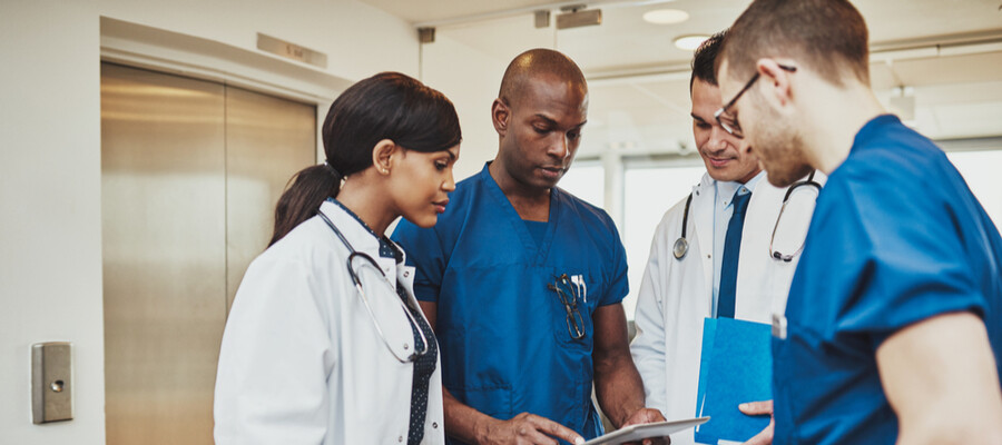 A team of nurses and doctors consult on a patient’s care.