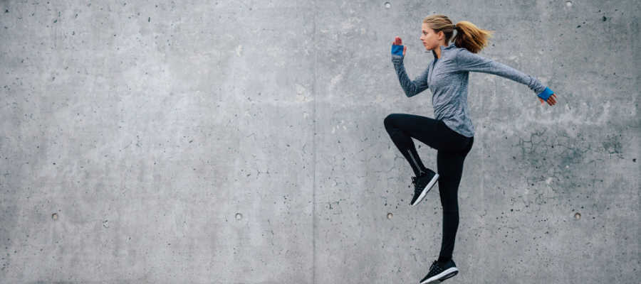 A female runner exercises next to a gray wall