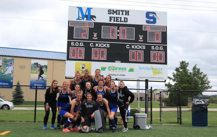 Marian University of Wisconsin’s women’s field hockey team pose for a picture in front of the field scoreboard