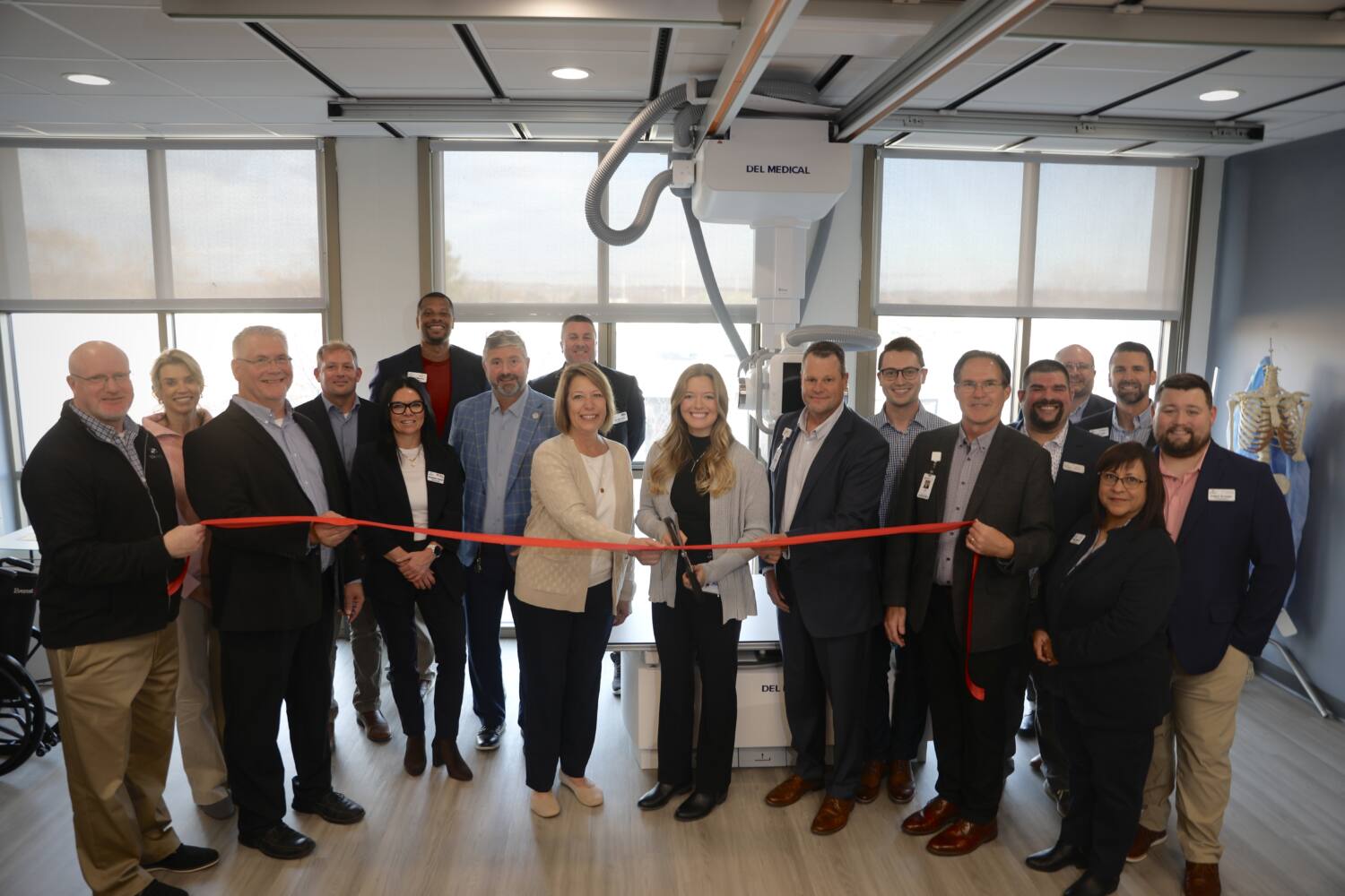 Multiple people within a radiologic classroom participating in a ribbon cutting ceremony.