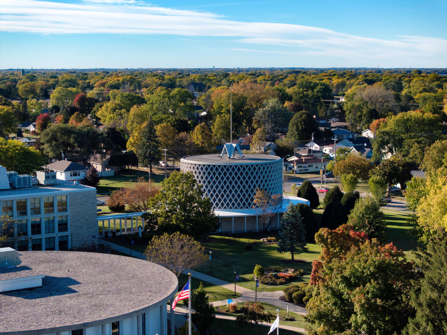 Outside view of Dorcas Chapel, A partial view or both the library and Agnes Hazotte Hall. Beginning of fall season, trees are green and orange, and a little red.